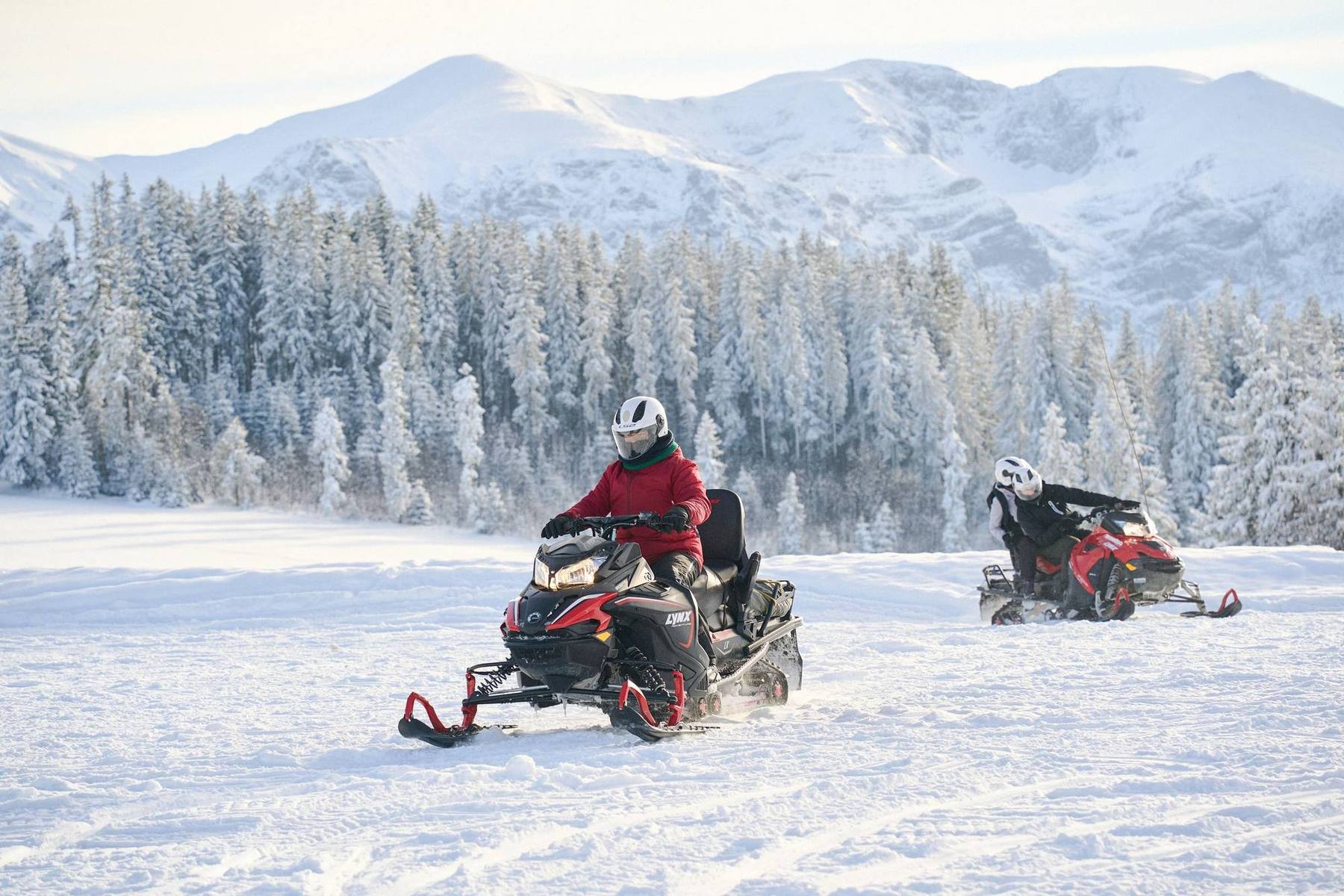 Lynx snowmobiles on a trail above Zakopane, snow-covered forest and the Tatra ridge behind