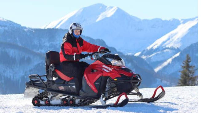 Rider on a red snowmobile against the Tatra Mountains - the TRIP tour